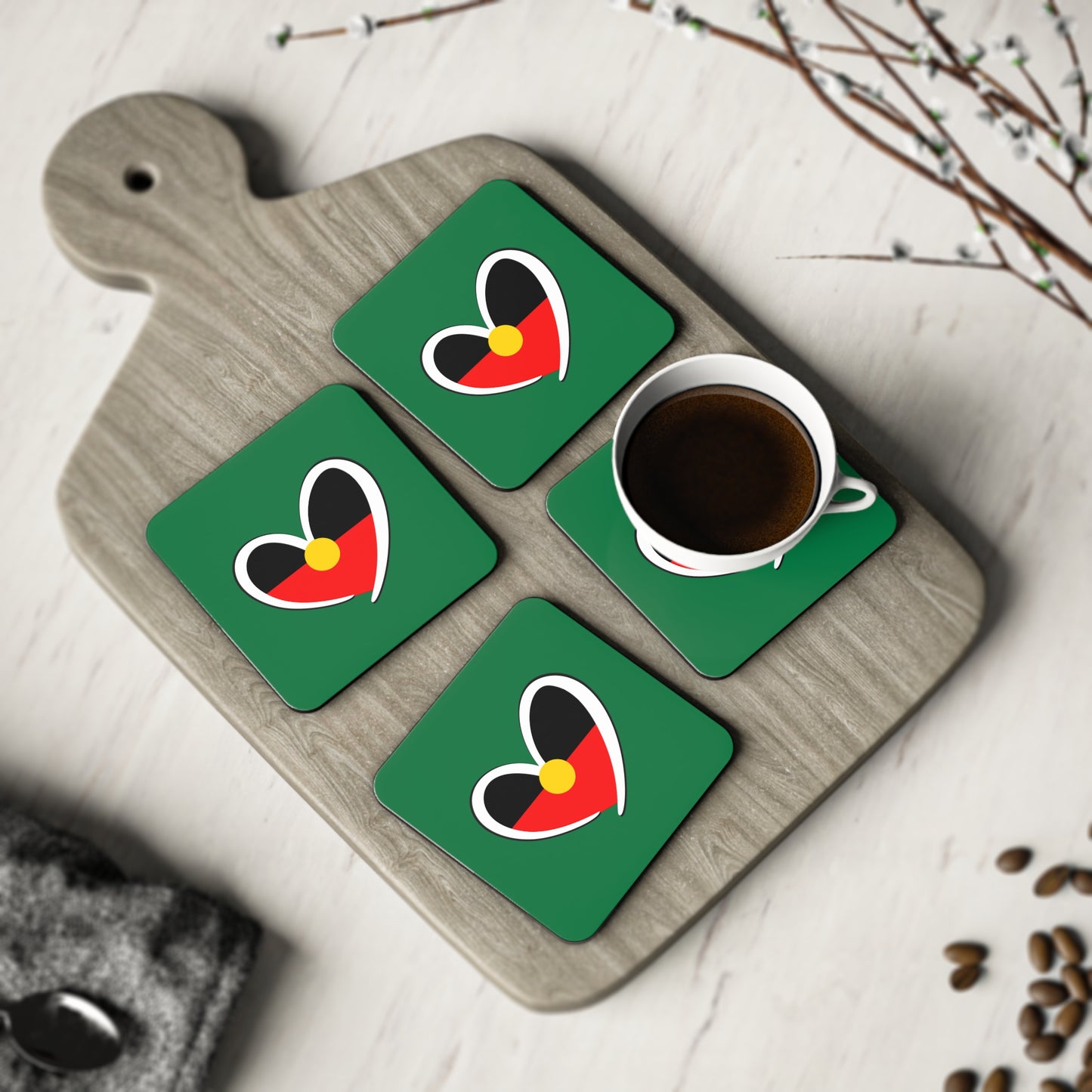 Set of four green Aboriginal heart square coasters styled on timber board for cultural elegance.