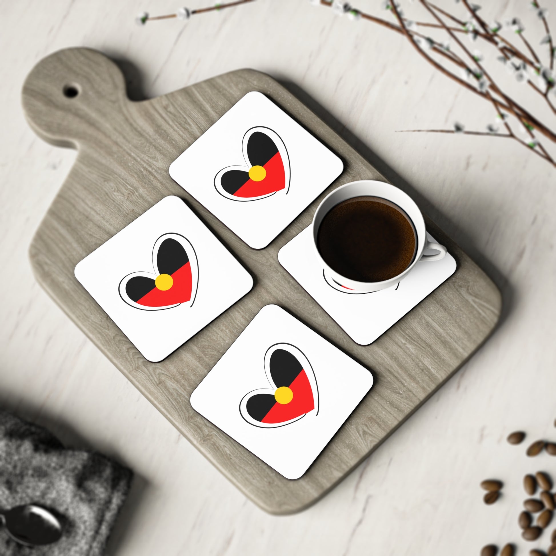 Set of four square white coasters displayed on serving board with cup and decorative setting.