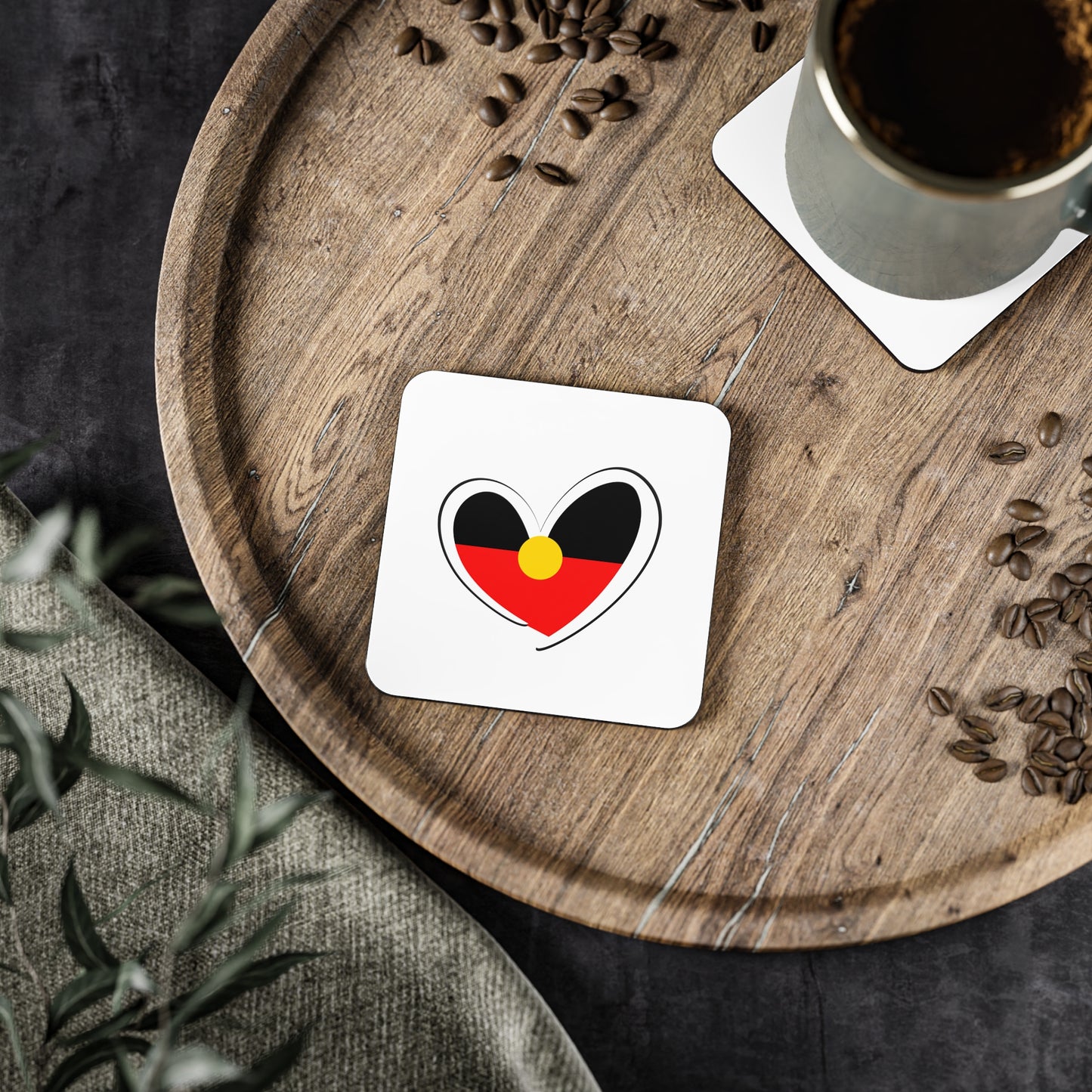 Square white Aboriginal Flag coaster on a wooden tray with coffee cup and coffee beans.