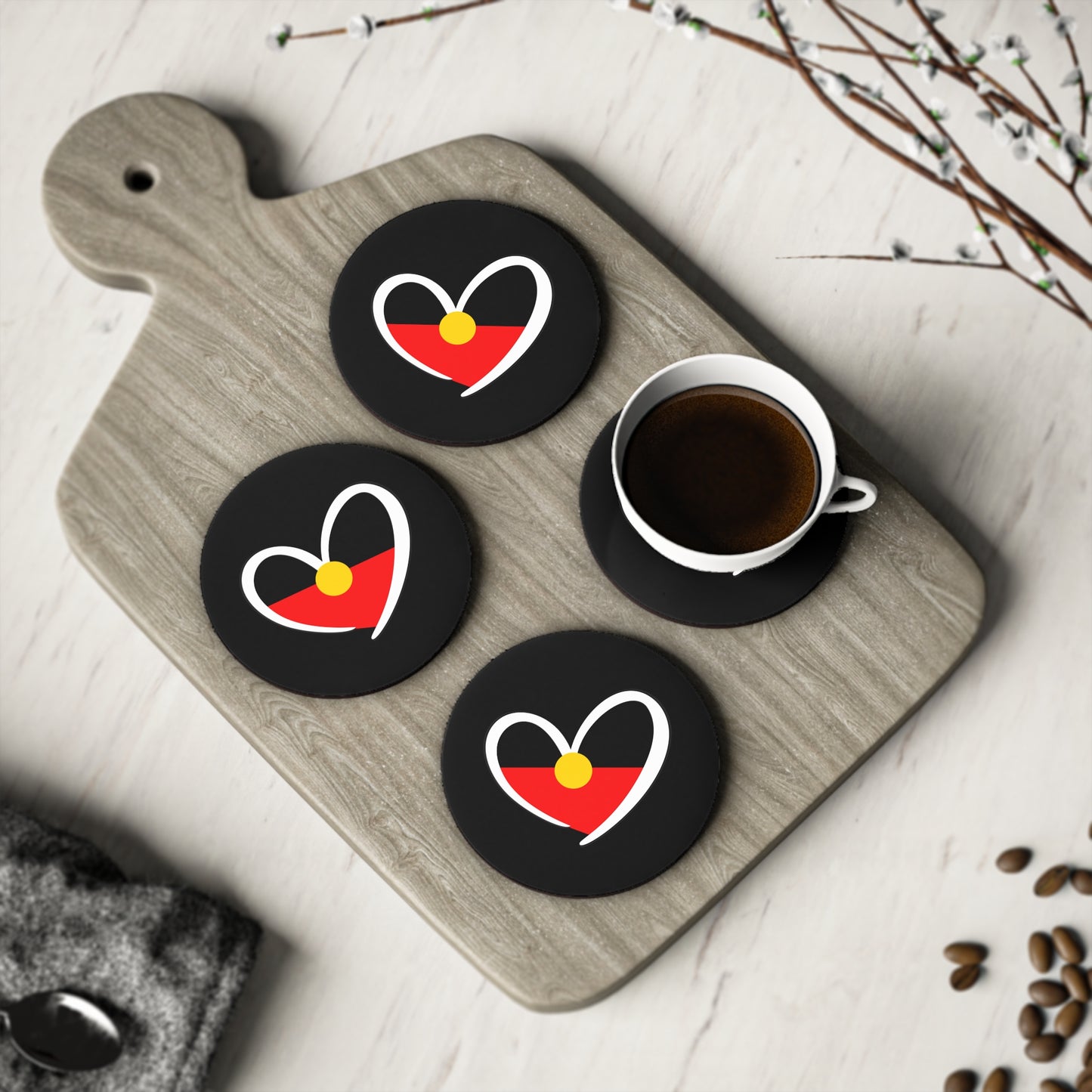 Group of four round black coasters on a light wood board, styled with coffee cup.