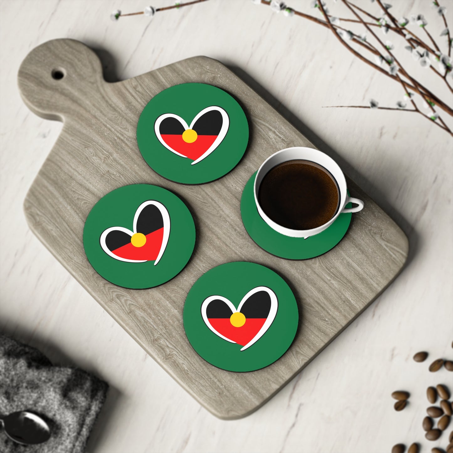 Set of round green Aboriginal heart coasters displayed with coffee, celebrating culture and unity.