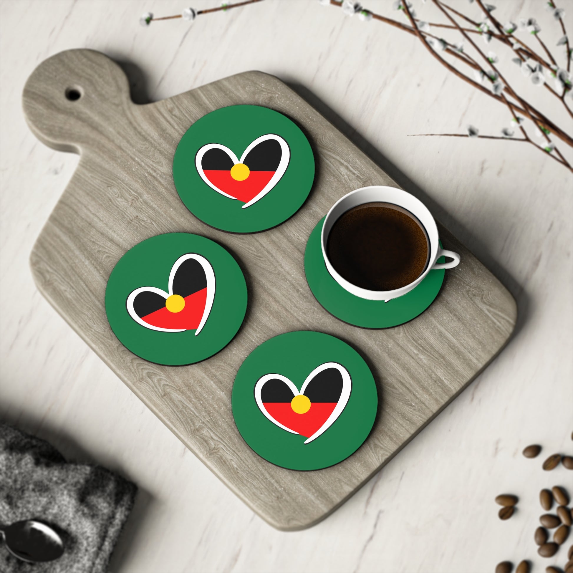 Set of round green Aboriginal heart coasters displayed with coffee, celebrating culture and unity.