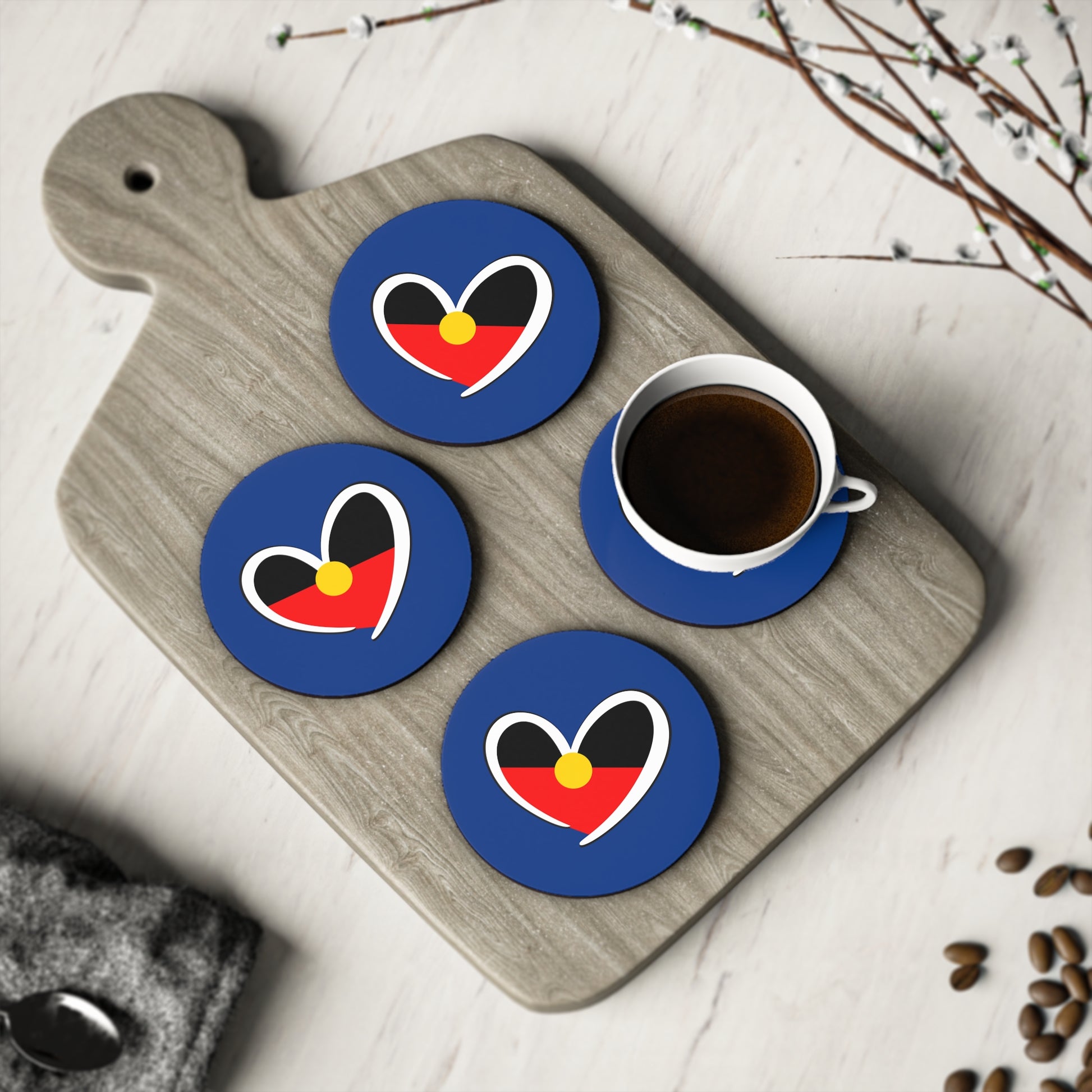 Four navy blue round Aboriginal coasters displayed on light board with coffee cup – cultural table decor.