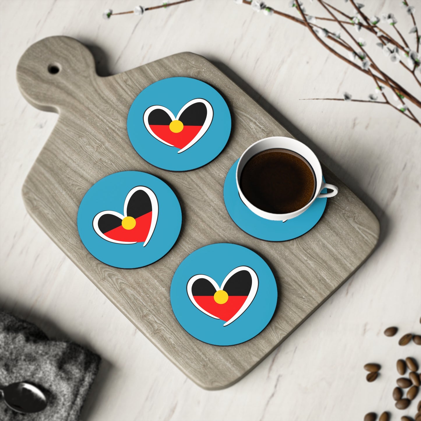 Set of round turquoise Aboriginal heart coasters displayed with coffee, celebrating culture and unity.