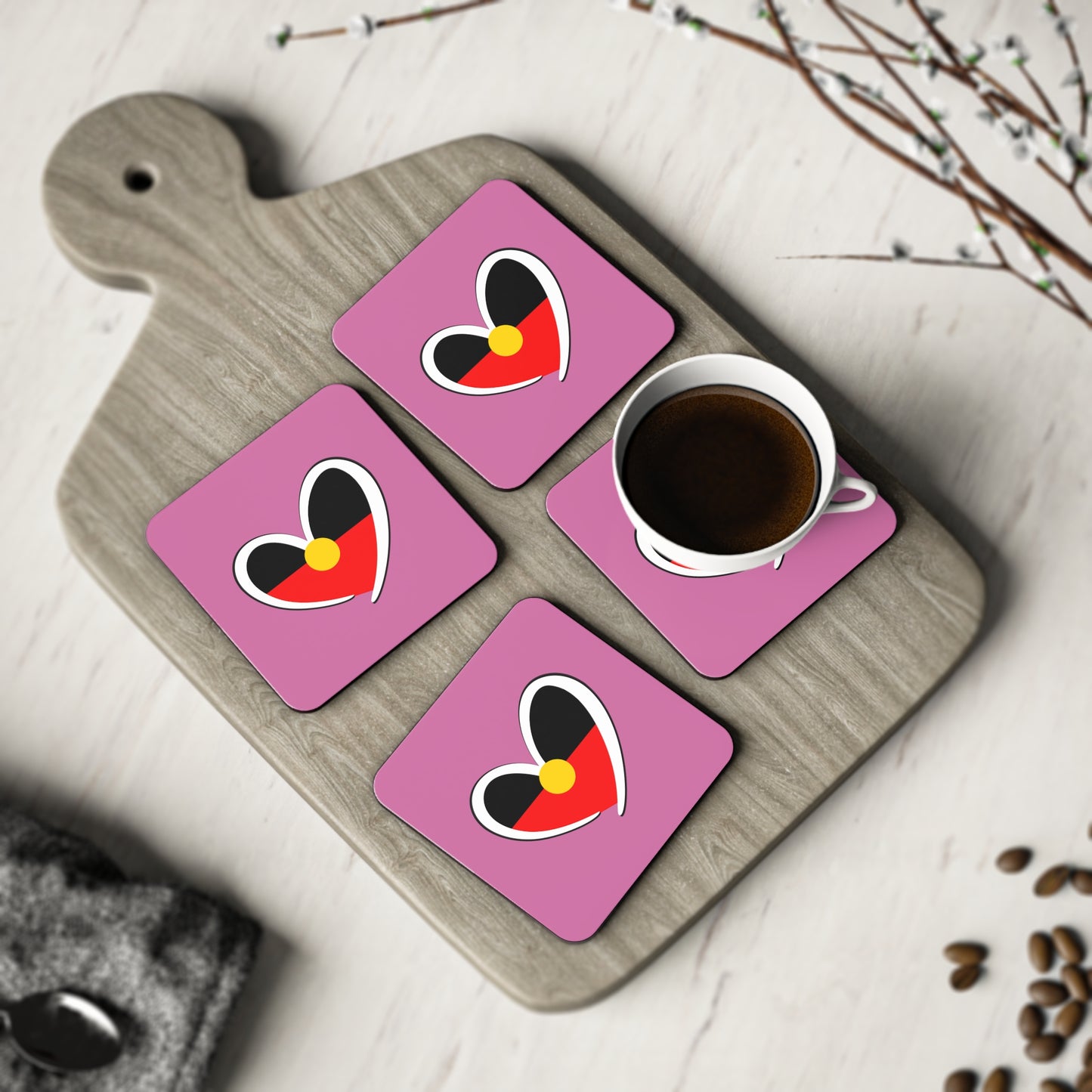 Four pink Aboriginal heart square coasters styled with coffee on board – meaningful and modern.
